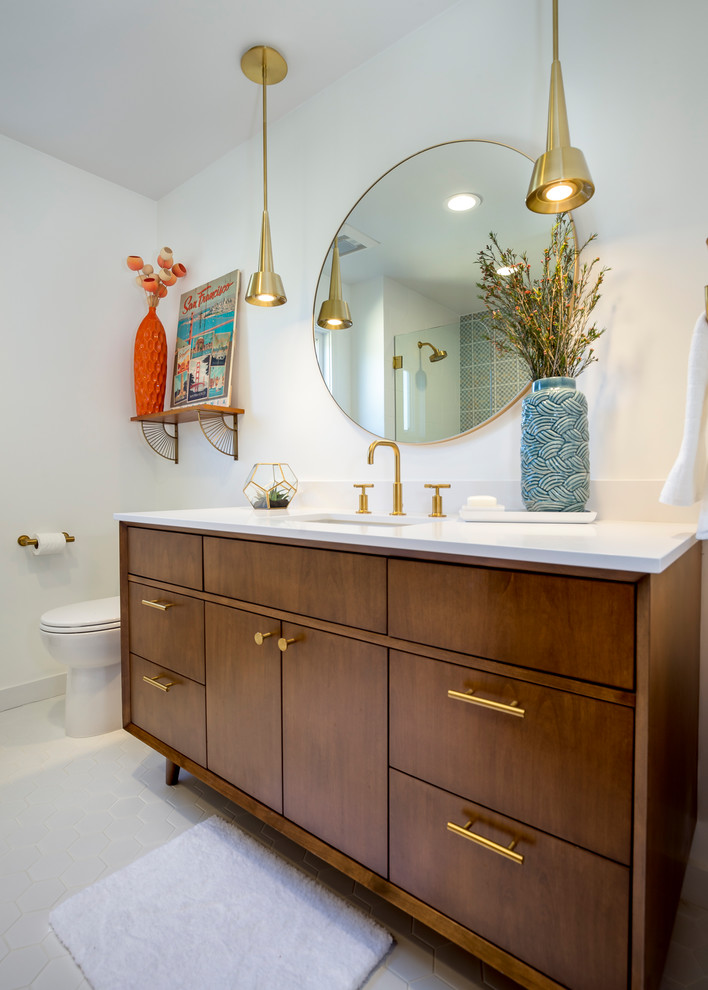 Photo of a mid-sized midcentury bathroom in Los Angeles with medium wood cabinets, a shower/bathtub combo, white tile, ceramic tile, white walls, engineered quartz benchtops, furniture-like cabinets, a drop-in tub, a two-piece toilet, porcelain floors, an undermount sink, white floor and a hinged shower door.