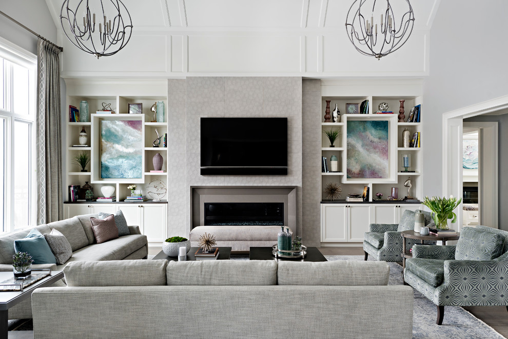 Design ideas for a large traditional enclosed living room in Toronto with grey walls, medium hardwood floors, a standard fireplace, a tile fireplace surround, a wall-mounted tv and brown floor.