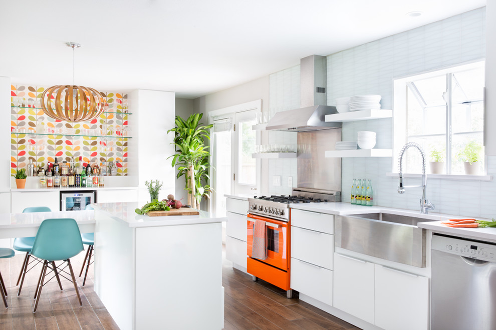 Photo of a mid-sized midcentury single-wall eat-in kitchen in Austin with a farmhouse sink, flat-panel cabinets, white cabinets, quartz benchtops, white splashback, glass tile splashback, stainless steel appliances, ceramic floors and with island.