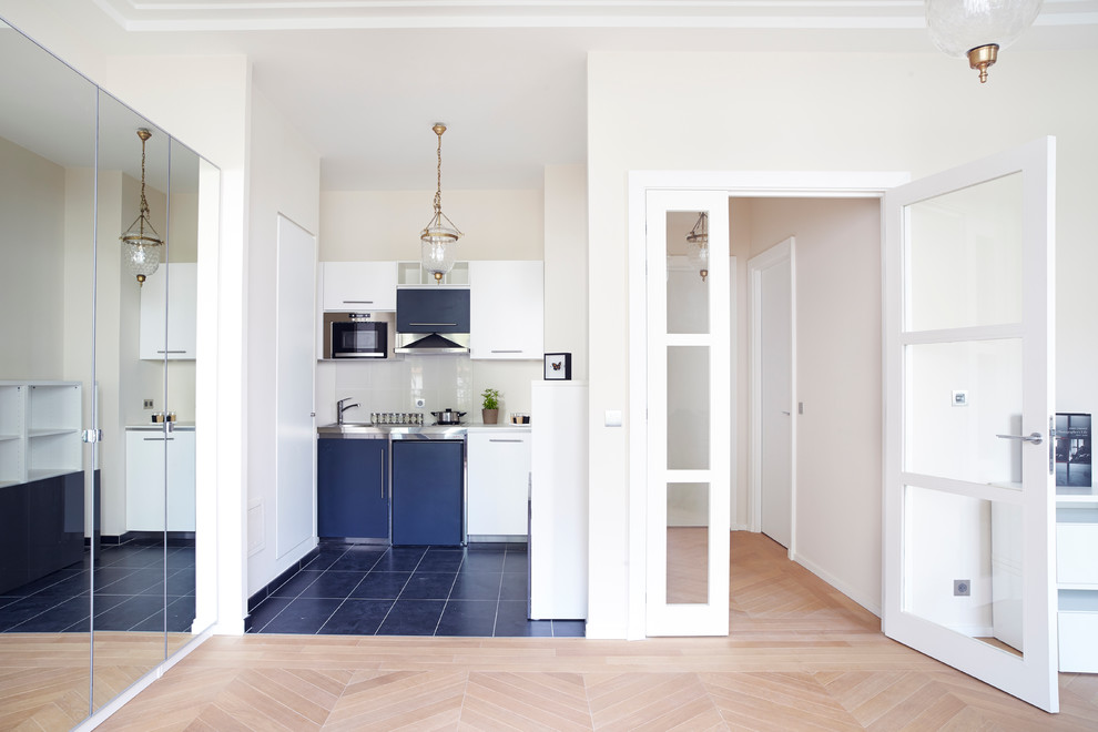 Photo of a small contemporary single-wall open plan kitchen in Paris with flat-panel cabinets, white cabinets, light hardwood floors and no island.