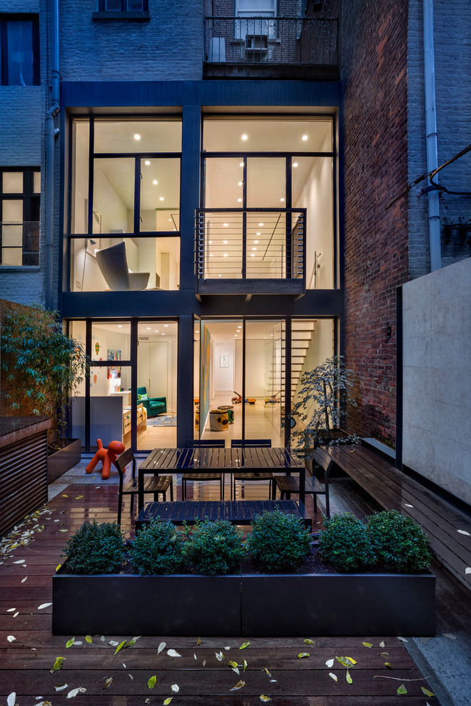 Photo of a contemporary three-storey glass townhouse exterior in New York.
