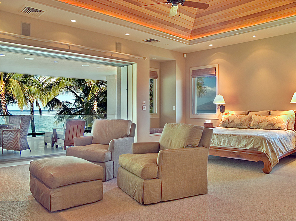 Inspiration for a large tropical master bedroom in Hawaii with beige walls and carpet.