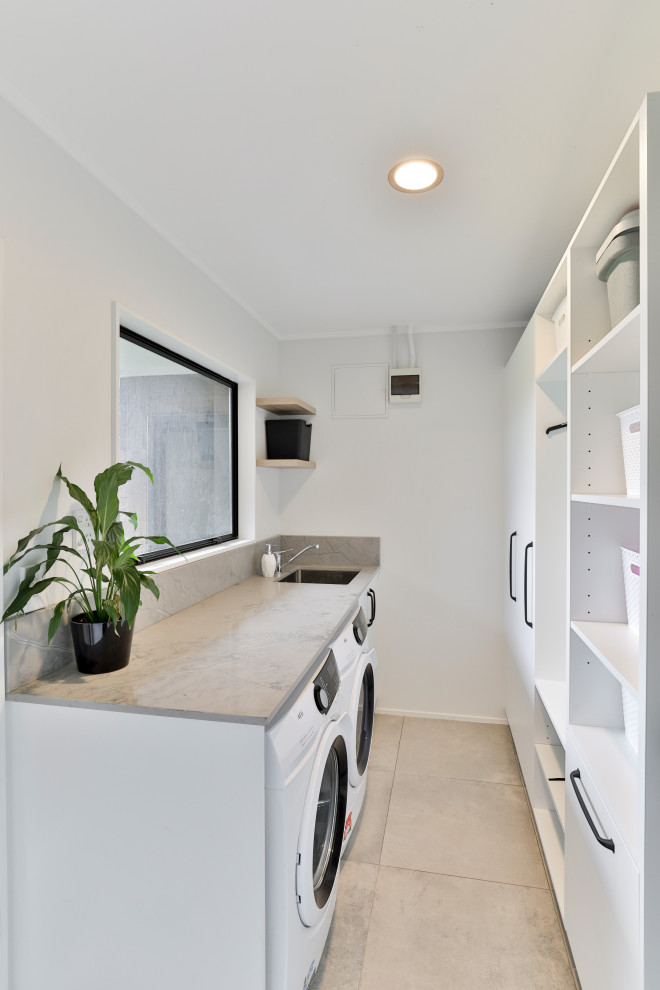 Laundry room - mid-sized modern laundry room idea in Auckland with an undermount sink, white cabinets and a side-by-side washer/dryer