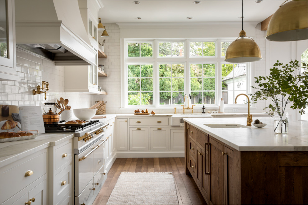 Kitchen pantry - large transitional u-shaped medium tone wood floor and brown floor kitchen pantry idea with a farmhouse sink, shaker cabinets, white cabinets, marble countertops, white backsplash, subway tile backsplash, paneled appliances, an island and white countertops