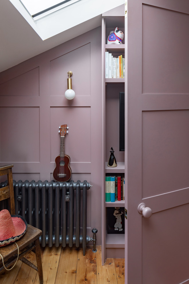 Idee per un soggiorno boho chic di medie dimensioni e aperto con libreria, pareti rosa, pavimento in legno massello medio, TV nascosta e pannellatura