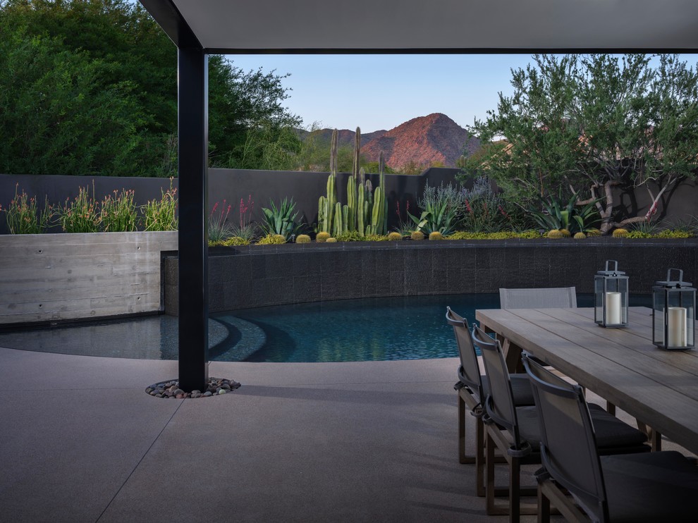 This is an example of a mid-sized contemporary backyard patio in Phoenix with with fireplace, concrete pavers and a roof extension.