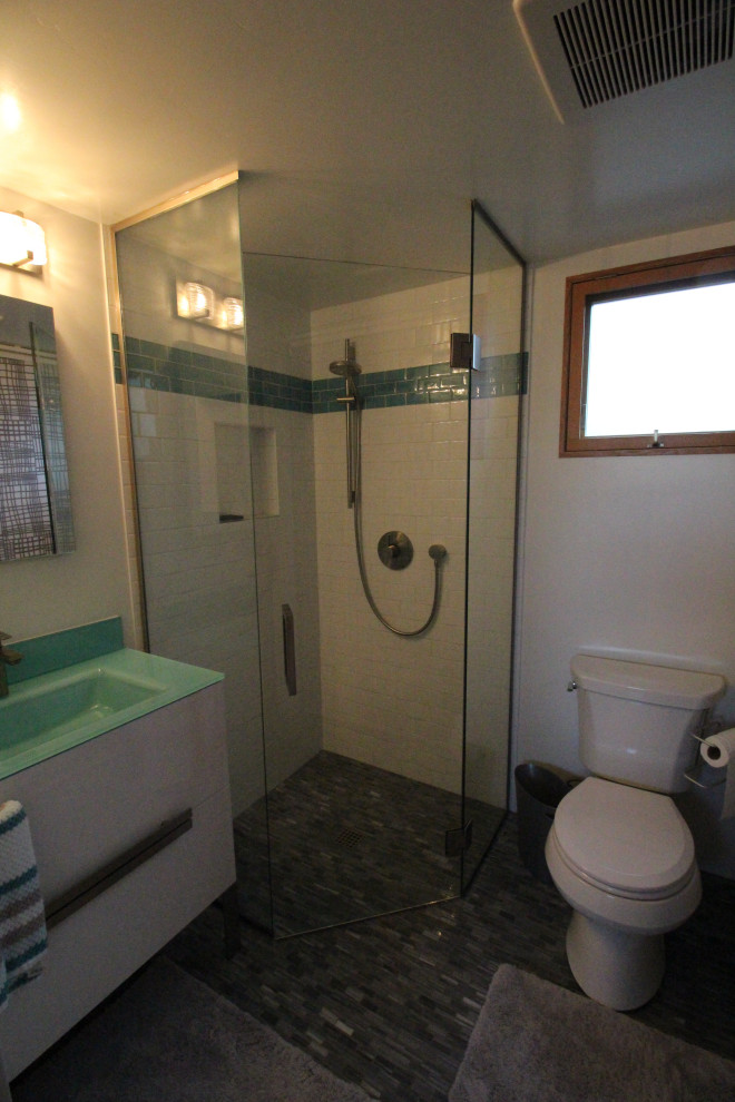 Photo of a small 3/4 bathroom in San Diego with furniture-like cabinets, white cabinets, a corner shower, a two-piece toilet, white tile, porcelain tile, yellow walls, marble floors, a console sink, glass benchtops, grey floor, a hinged shower door and blue benchtops.