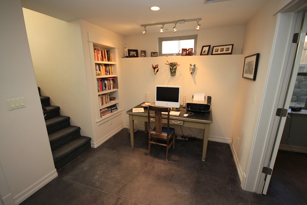This is an example of a mid-sized arts and crafts study room in Denver with white walls, concrete floors, no fireplace and a freestanding desk.