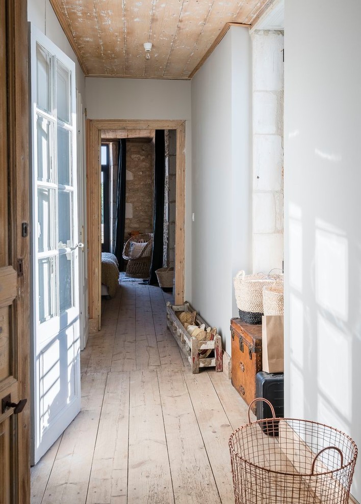 This is an example of a mediterranean hallway in Other with white walls, light hardwood floors and beige floor.