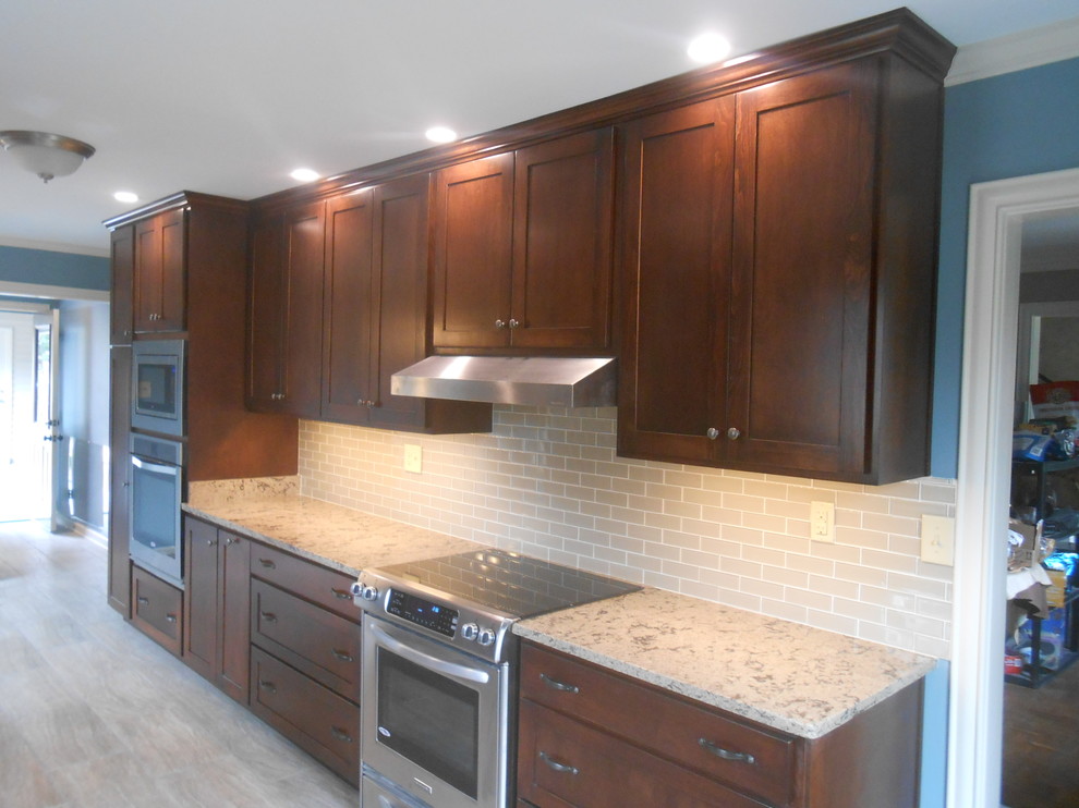 Example of a mid-sized transitional galley porcelain tile eat-in kitchen design with an undermount sink, shaker cabinets, dark wood cabinets, quartz countertops, beige backsplash, glass sheet backsplash, stainless steel appliances, blue walls and no island