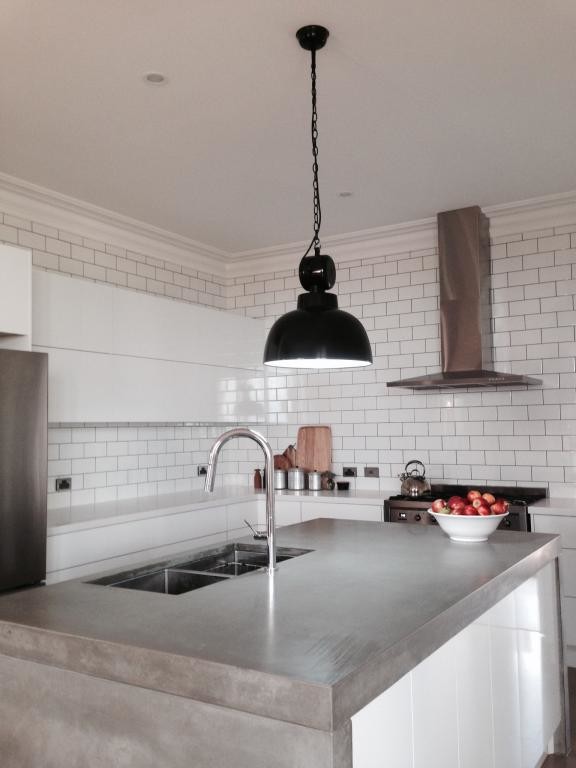 Mid-sized contemporary l-shaped kitchen in Adelaide with a double-bowl sink, flat-panel cabinets, white cabinets, concrete benchtops, white splashback, subway tile splashback, stainless steel appliances and with island.