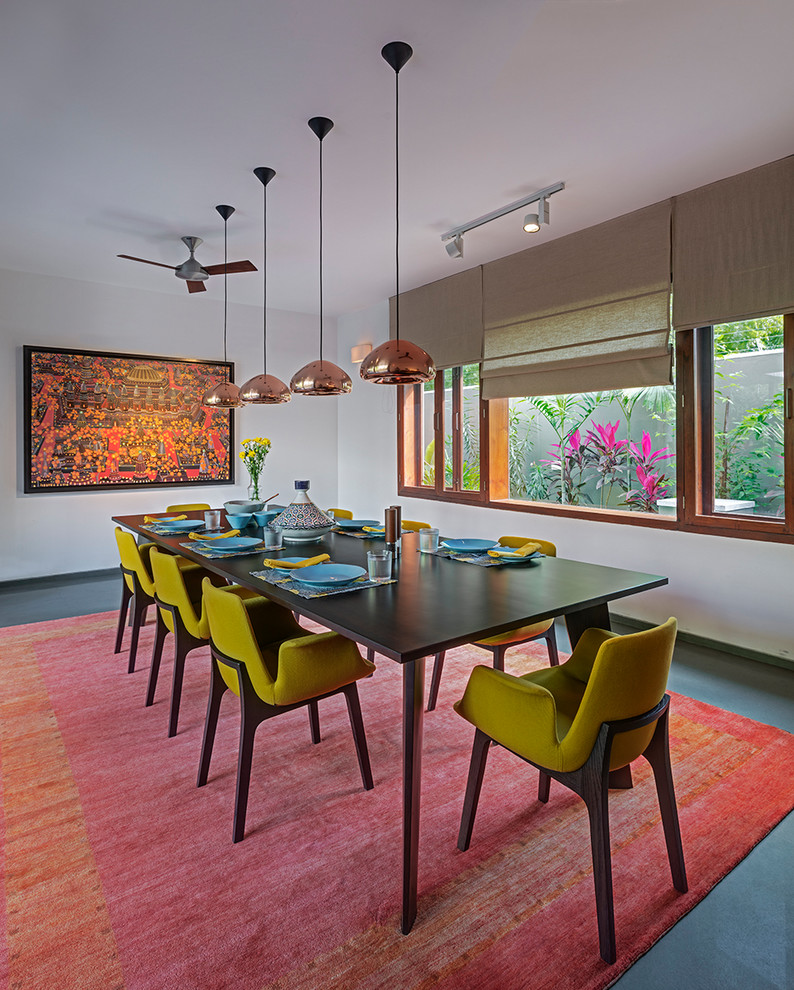 This is an example of a mid-sized contemporary separate dining room in Hyderabad with white walls, concrete floors and grey floor.