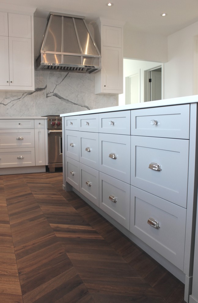 This is an example of a large traditional l-shaped eat-in kitchen in Calgary with a single-bowl sink, shaker cabinets, white cabinets, quartz benchtops, grey splashback, stone slab splashback, stainless steel appliances, medium hardwood floors and with island.