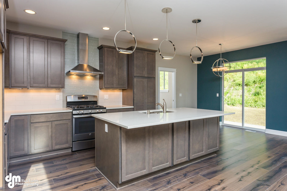 Mid-sized arts and crafts galley open plan kitchen in Other with shaker cabinets, quartzite benchtops, stainless steel appliances, with island, a double-bowl sink, light wood cabinets, green splashback, glass tile splashback and medium hardwood floors.