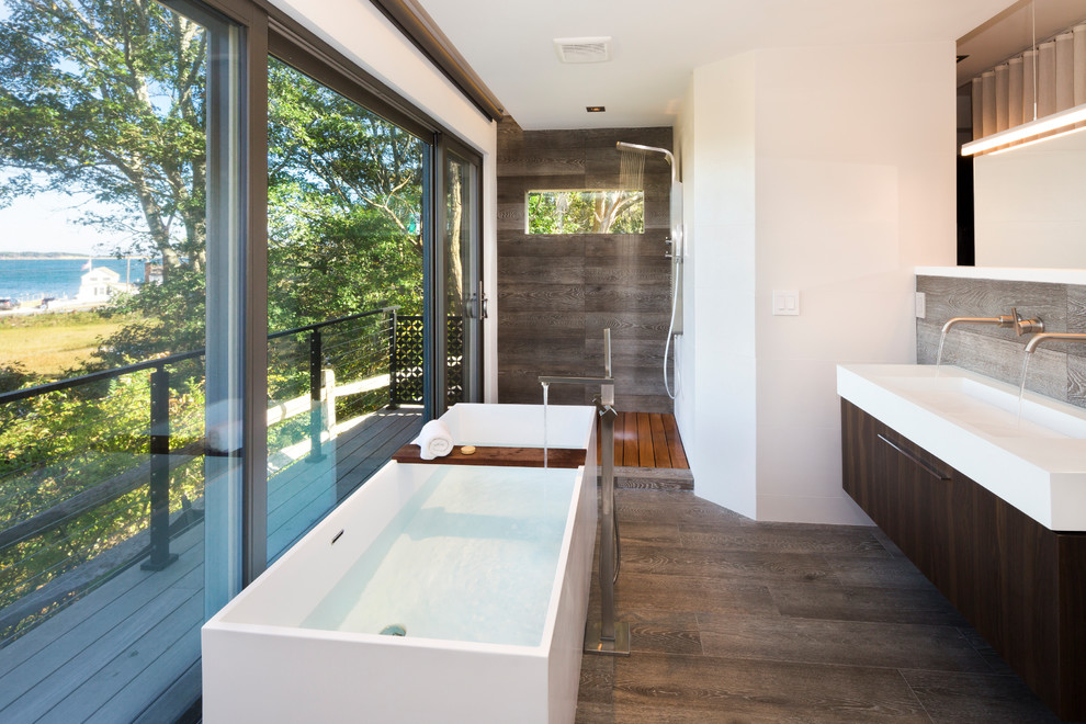 This is an example of a contemporary master bathroom in Other with flat-panel cabinets, dark wood cabinets, a freestanding tub, a corner shower, brown tile, white walls, dark hardwood floors, a trough sink, brown floor and white benchtops.