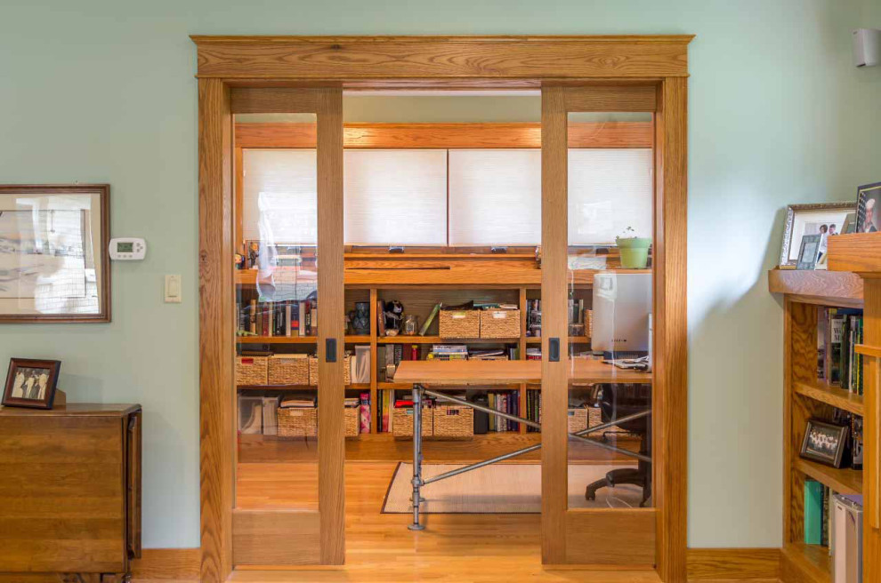 Cette photo montre un bureau craftsman de taille moyenne avec une bibliothèque ou un coin lecture, un mur vert, parquet clair, aucune cheminée, un bureau indépendant, un sol marron, un plafond en papier peint et boiseries.