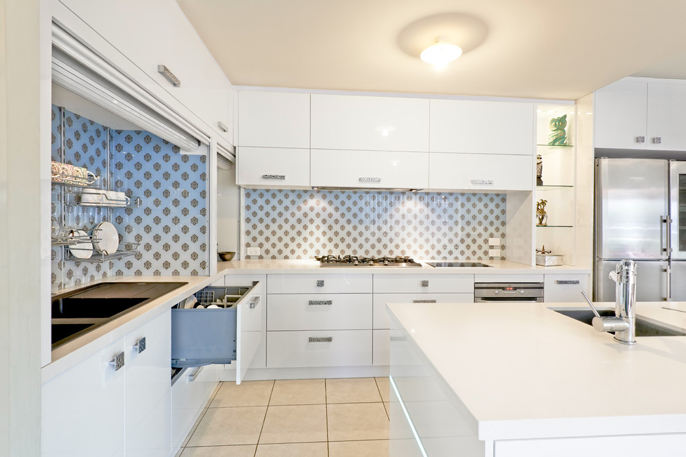 Photo of a large contemporary l-shaped eat-in kitchen in Melbourne with a drop-in sink, flat-panel cabinets, white cabinets, quartz benchtops, beige splashback, glass sheet splashback, stainless steel appliances, ceramic floors and with island.