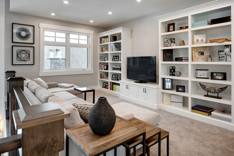 This is an example of a large transitional loft-style family room in Calgary with a library, grey walls, carpet, a freestanding tv and grey floor.