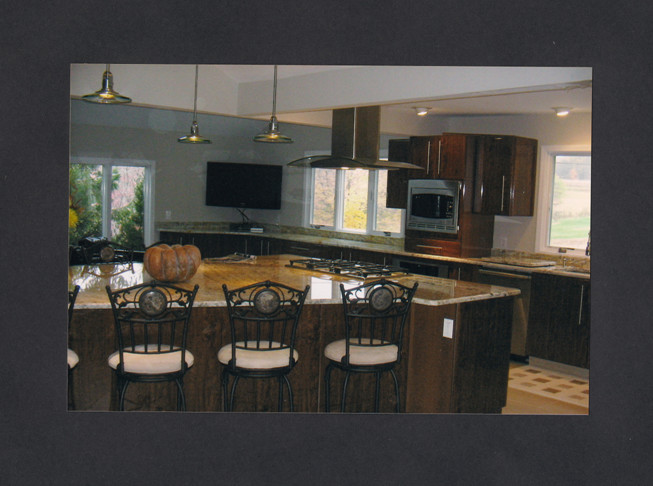 Inspiration for a large transitional ceramic tile kitchen remodel in New York with an undermount sink, flat-panel cabinets, dark wood cabinets, granite countertops, stone slab backsplash, stainless steel appliances and an island