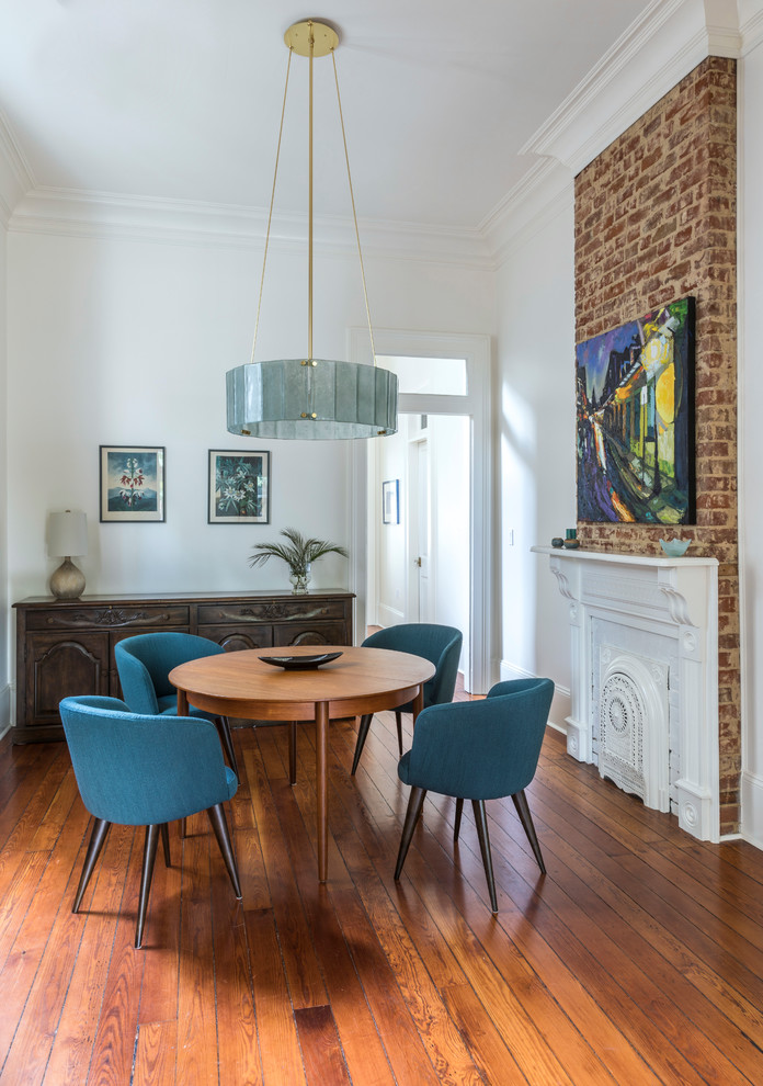 Photo of a mid-sized transitional separate dining room in New Orleans with white walls, medium hardwood floors, a standard fireplace, brown floor and a wood fireplace surround.
