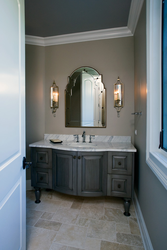 Large traditional powder room in Chicago with raised-panel cabinets, grey cabinets, beige tile, marble benchtops, grey walls, limestone floors, an undermount sink and stone slab.
