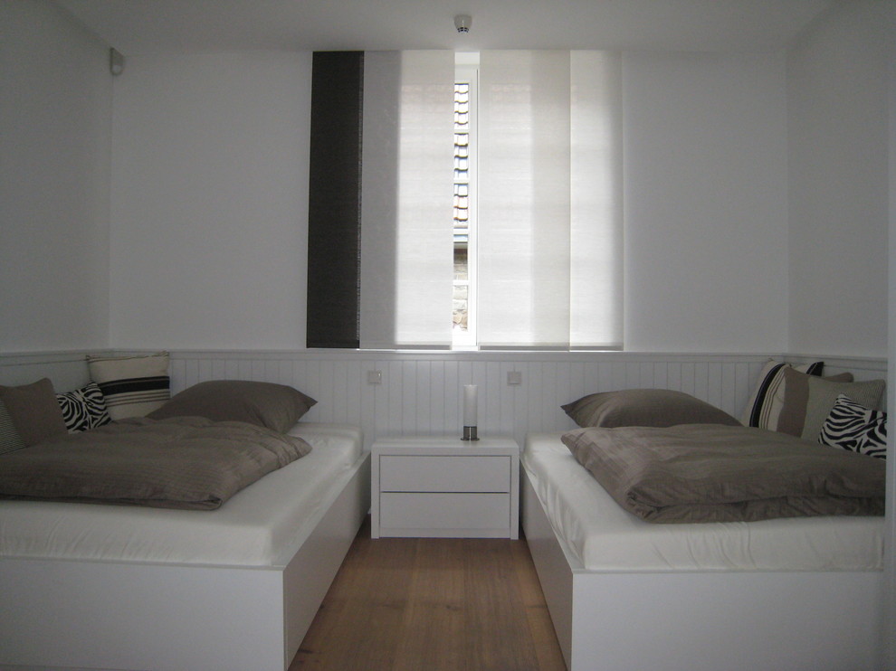 Mittelgroßes Landhaus Gästezimmer ohne Kamin mit weißer Wandfarbe, braunem Holzboden und braunem Boden in Köln