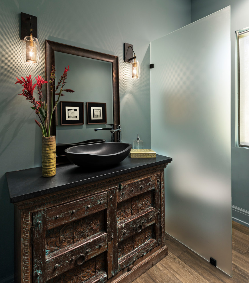 Photo of a mid-sized transitional 3/4 bathroom in Detroit with dark wood cabinets, blue walls, medium hardwood floors, a vessel sink, granite benchtops, brown floor and black benchtops.