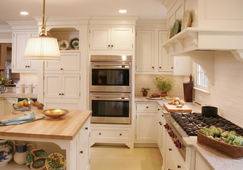 This is an example of a traditional u-shaped eat-in kitchen in New York with an undermount sink, white cabinets, granite benchtops, white splashback, subway tile splashback and panelled appliances.