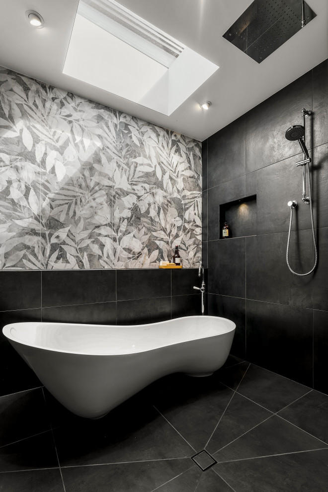 Mid-sized contemporary 3/4 bathroom in Melbourne with open cabinets, a freestanding tub, a curbless shower, a wall-mount toilet, black tile, porcelain tile, black walls, porcelain floors, an integrated sink, solid surface benchtops, black floor, an open shower, white benchtops, a niche, a single vanity and a freestanding vanity.