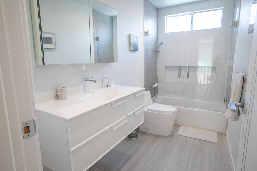 Idéer för ett mellanstort klassiskt vit badrum för barn, med släta luckor, vita skåp, ett badkar i en alkov, en dusch i en alkov, en toalettstol med hel cisternkåpa, vit kakel, vita väggar, vinylgolv, ett väggmonterat handfat, marmorbänkskiva, grått golv och dusch med gångjärnsdörr