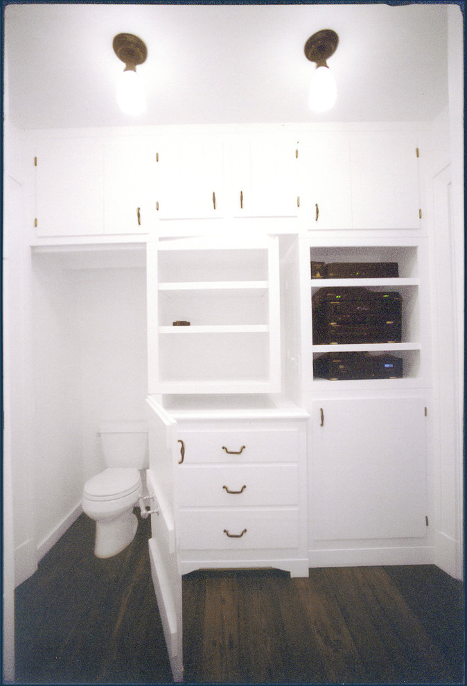 Inspiration for a mid-sized country men's walk-in wardrobe in New York with recessed-panel cabinets, white cabinets and dark hardwood floors.