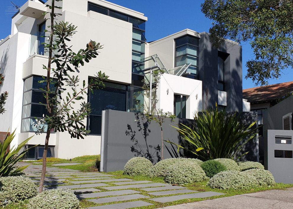 Photo of a mid-sized and australian native contemporary front yard full sun driveway in Sydney with natural stone pavers.