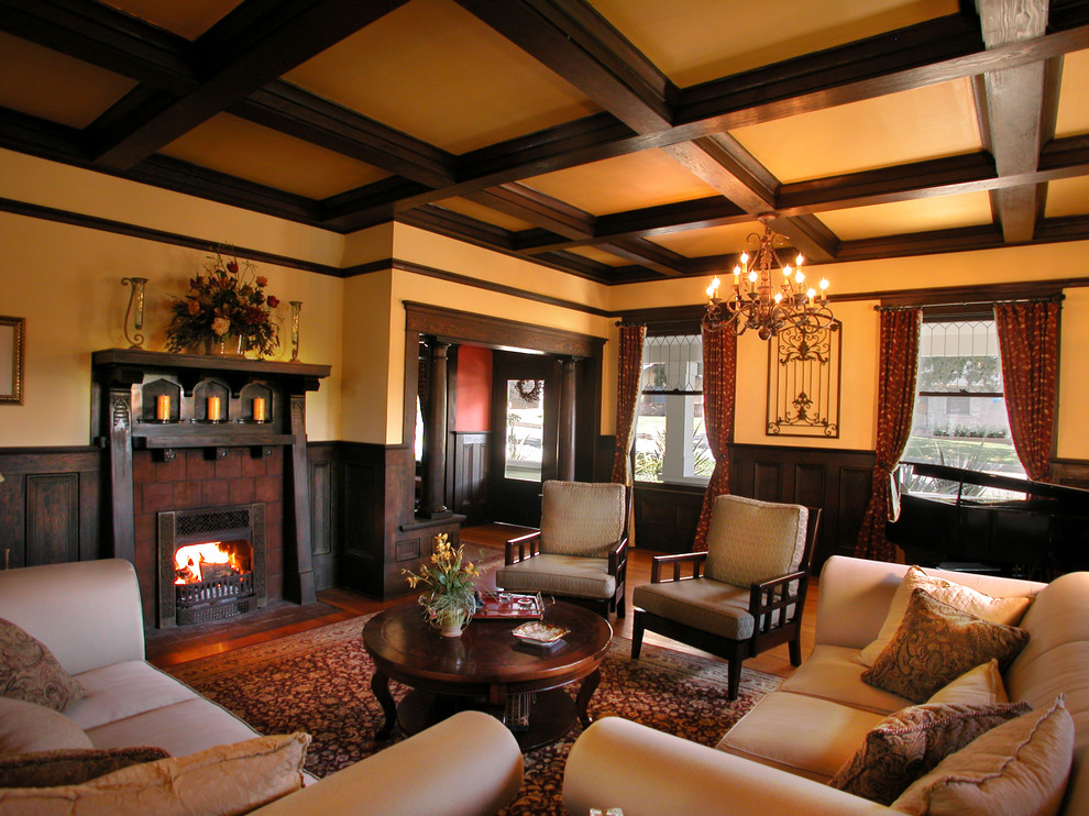 Photo of a mid-sized arts and crafts enclosed living room in Los Angeles with yellow walls, dark hardwood floors, a standard fireplace, a wood fireplace surround and brown floor.