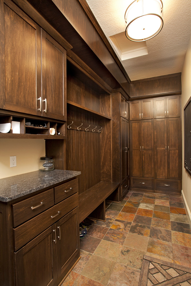 This is an example of a mid-sized country gender-neutral walk-in wardrobe in Minneapolis with shaker cabinets, dark wood cabinets and terra-cotta floors.