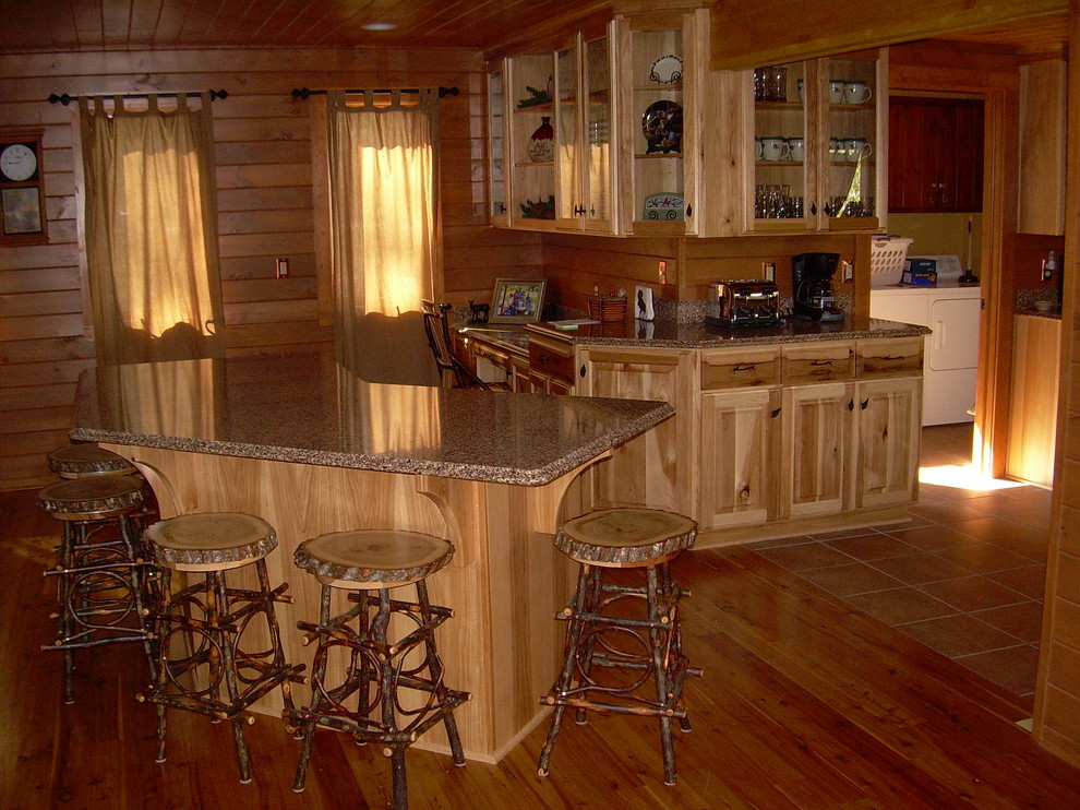Example of a mid-sized mountain style u-shaped medium tone wood floor and brown floor open concept kitchen design with glass-front cabinets, light wood cabinets, granite countertops, brown backsplash, wood backsplash, stainless steel appliances and an island