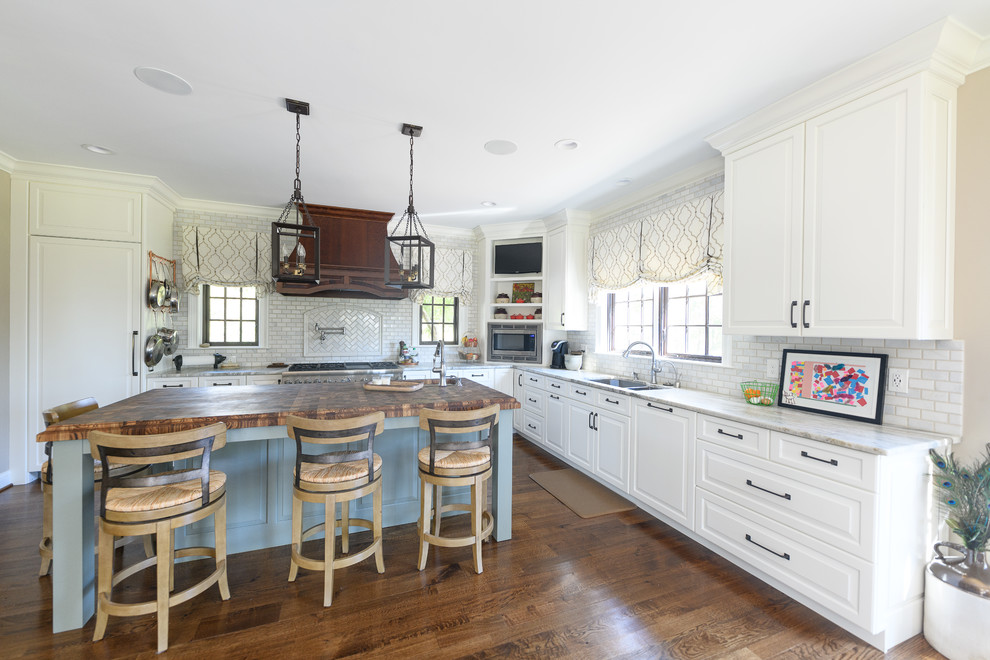 Kitchen - large transitional l-shaped dark wood floor and brown floor kitchen idea with an undermount sink, raised-panel cabinets, white cabinets, quartzite countertops, white backsplash, marble backsplash, stainless steel appliances and an island