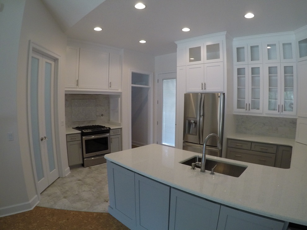 Photo of a mid-sized arts and crafts eat-in kitchen in Miami with an undermount sink, shaker cabinets, white cabinets, quartz benchtops, grey splashback, glass tile splashback, stainless steel appliances, light hardwood floors, with island, grey floor and white benchtop.