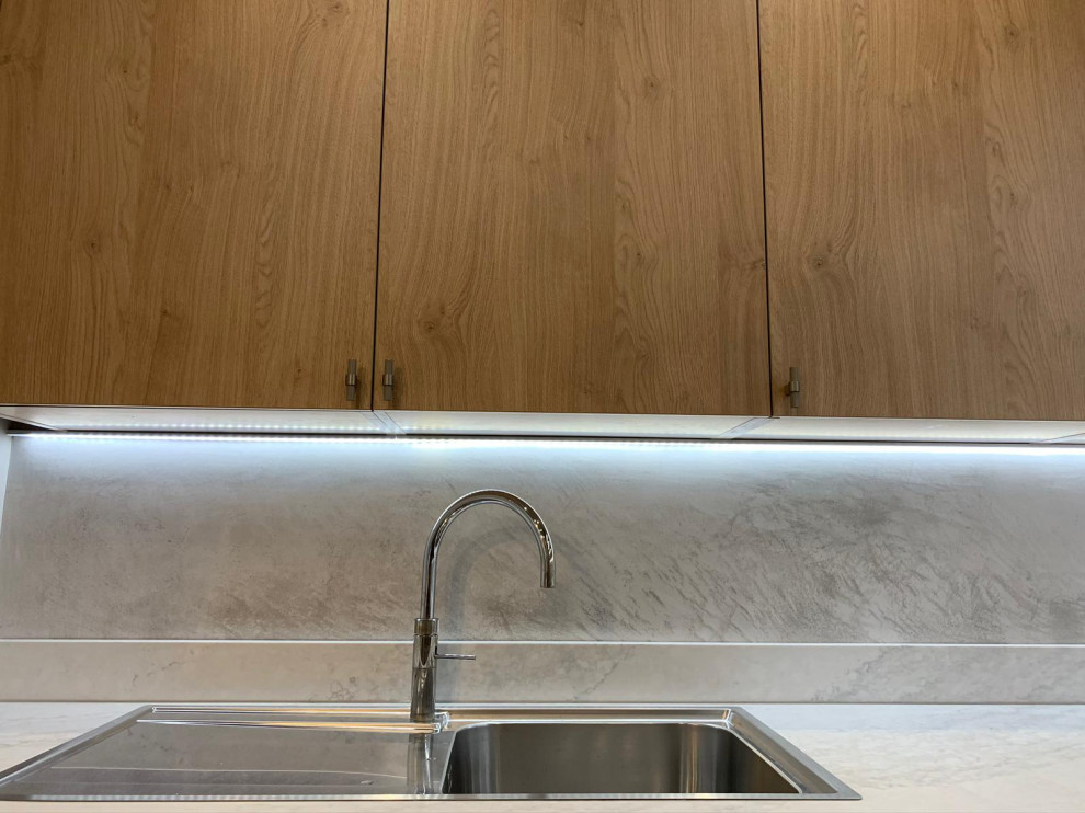 Immagine di una cucina a L industriale chiusa e di medie dimensioni con lavello a vasca singola, ante lisce, ante in legno scuro, top in superficie solida, paraspruzzi grigio, penisola e top bianco