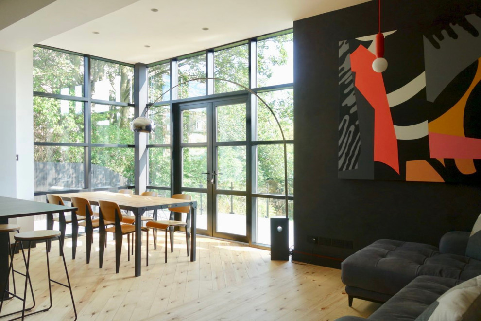 Photo of a mid-sized scandinavian u-shaped eat-in kitchen in Other with a double-bowl sink, flat-panel cabinets, black cabinets, quartzite benchtops, panelled appliances, light hardwood floors and black benchtop.