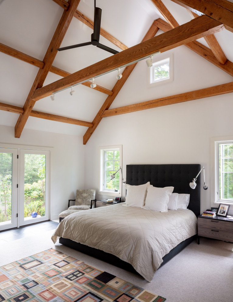 This is an example of a large country master bedroom in Providence with white walls, carpet and beige floor.
