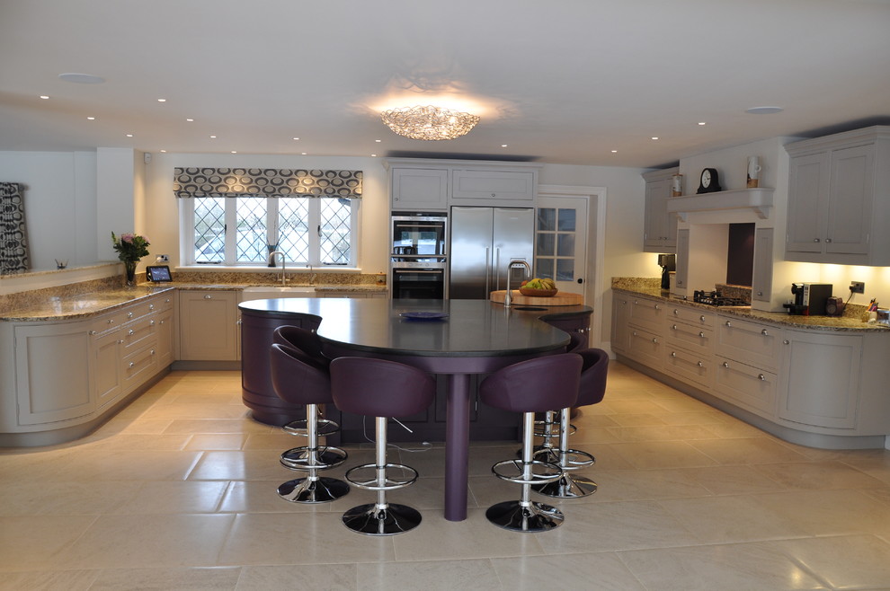 This is an example of a large transitional u-shaped eat-in kitchen in Hertfordshire with a drop-in sink, recessed-panel cabinets, grey cabinets, granite benchtops, black splashback, stainless steel appliances, ceramic floors and with island.