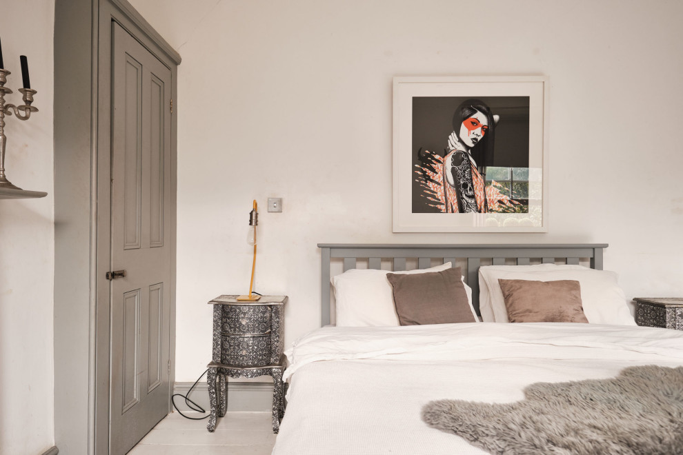 Mittelgroßes Stilmix Hauptschlafzimmer mit weißer Wandfarbe, gebeiztem Holzboden, Kamin, Kaminumrandung aus Holz und weißem Boden in London