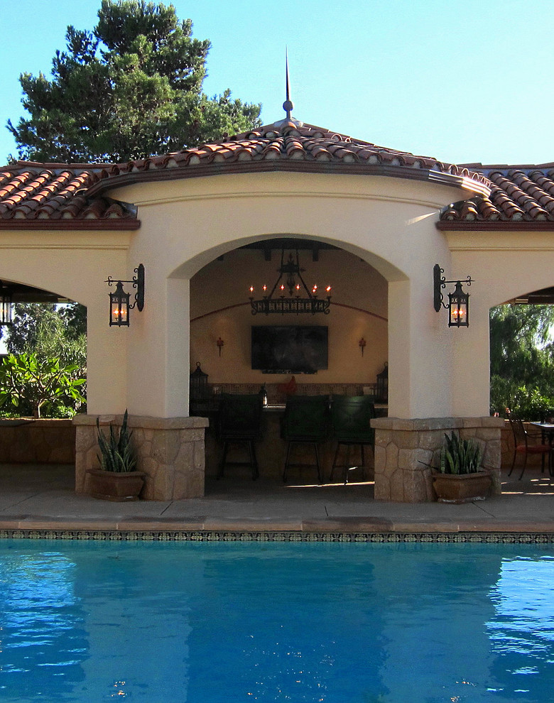 Inspiration for a mid-sized mediterranean backyard rectangular pool in Santa Barbara with a pool house and stamped concrete.