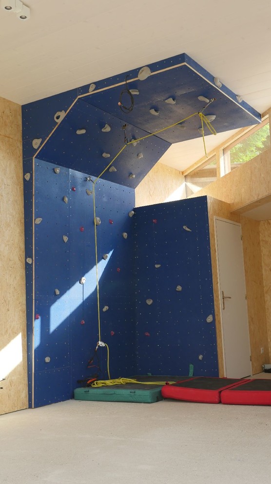 Photo of a large contemporary home climbing wall in Paris with beige walls, concrete floors and black floor.