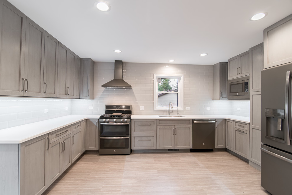 Enclosed kitchen - mid-sized transitional u-shaped vinyl floor and gray floor enclosed kitchen idea in Chicago with an undermount sink, recessed-panel cabinets, gray cabinets, quartzite countertops, gray backsplash, subway tile backsplash and stainless steel appliances