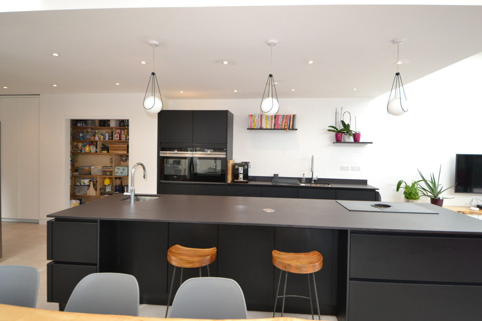 This is an example of a Large contemporary Galley open plan kitchen in Dublin With a Built-in Sink, Open Cabinets, Cement Flooring, an Island and Exposed Beams.