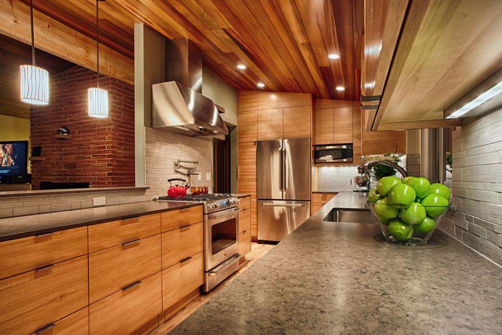 This is an example of a mid-sized contemporary galley open plan kitchen in Seattle with an undermount sink, flat-panel cabinets, medium wood cabinets, grey splashback, porcelain splashback, stainless steel appliances and medium hardwood floors.