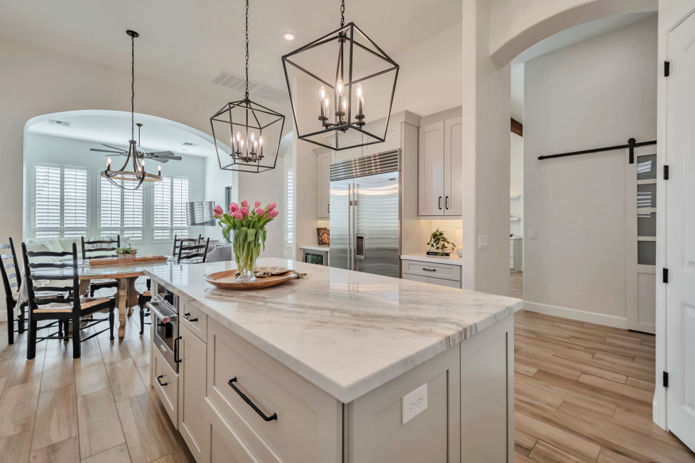 Kitchen - large transitional u-shaped porcelain tile, brown floor and exposed beam kitchen idea in Phoenix with a farmhouse sink, shaker cabinets, gray cabinets, quartzite countertops, white backsplash, porcelain backsplash, stainless steel appliances, an island and white countertops