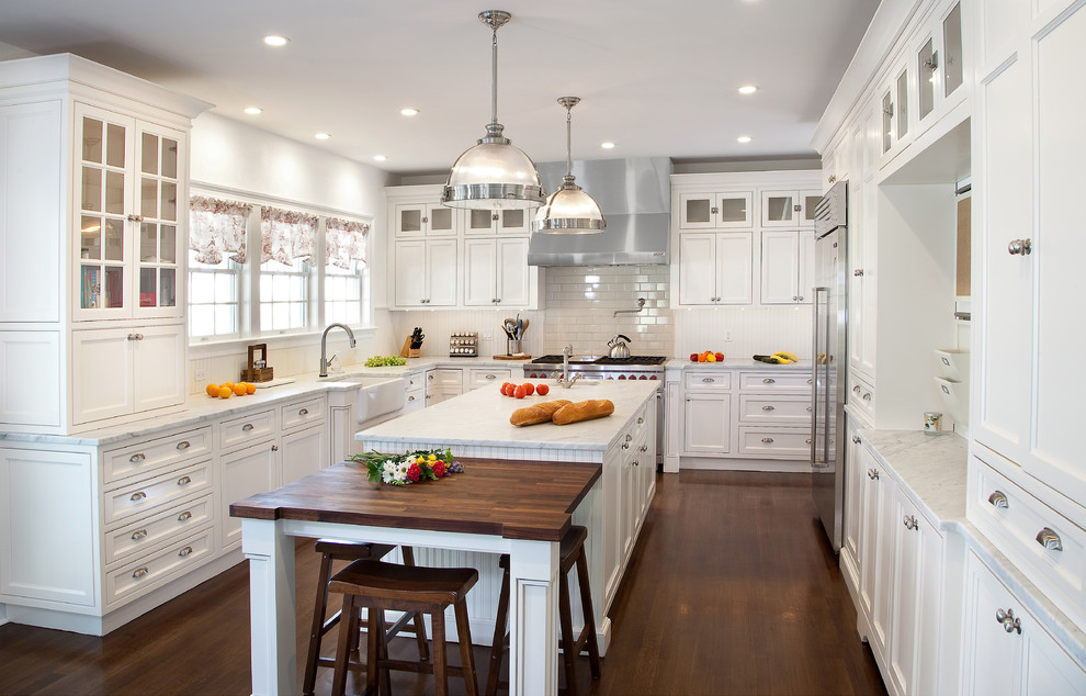 Mid-sized traditional u-shaped kitchen in New York with a farmhouse sink, beaded inset cabinets, white cabinets, marble benchtops, white splashback, subway tile splashback, stainless steel appliances, dark hardwood floors and with island.