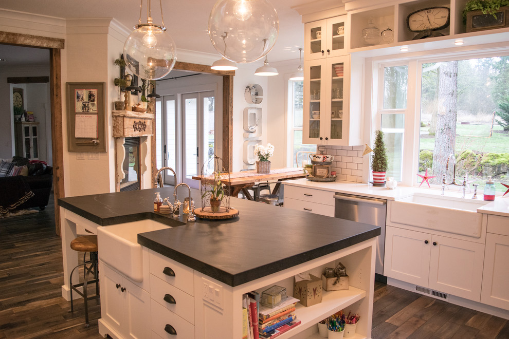 Design ideas for a large country u-shaped eat-in kitchen in Portland with a farmhouse sink, shaker cabinets, white cabinets, white splashback, subway tile splashback, stainless steel appliances, dark hardwood floors and with island.